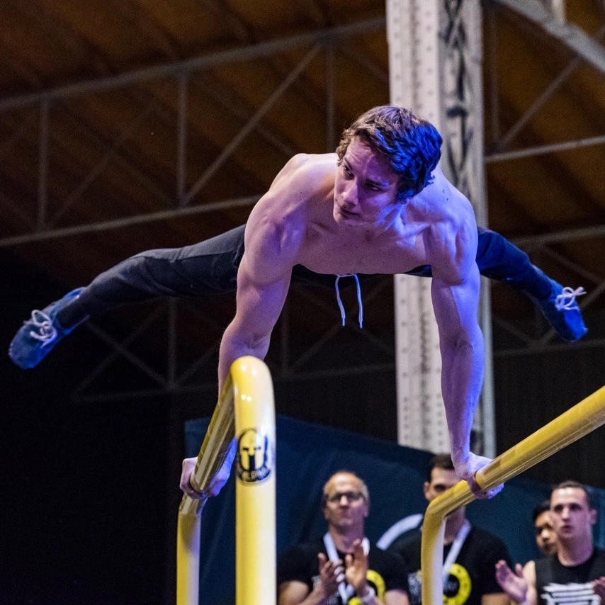 Denis Piccolo holding a straddle planche in competition