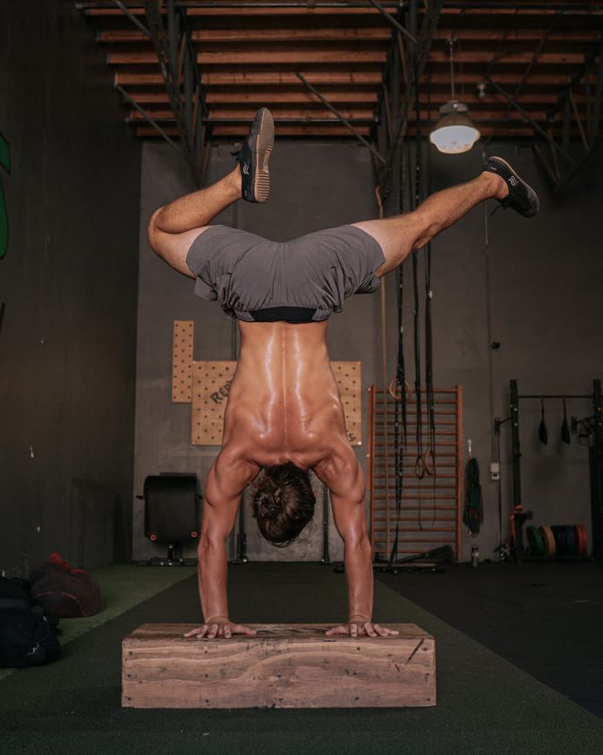 Garrett Kuljian holding a straddle handstand